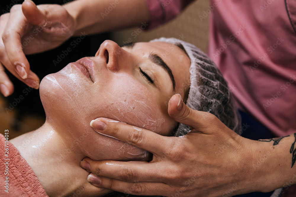 Obraz premium The woman gets a facial massage at the spa