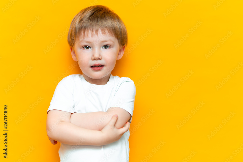 cheerful little boy child standing isolated over yellow background. Looking camera. with blonde hair mixed race central Asian and german
