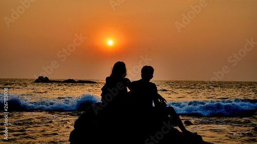 silhouette of a couple sitting by the beach