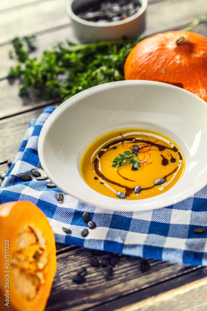 Pumpkin cream soup with seeds and parsley on kitchen table Pumpkin cream soup with seeds and parsley on kitchen table