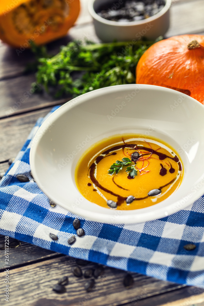 Pumpkin cream soup with seeds and parsley on kitchen table Pumpkin cream soup with seeds and parsley on kitchen table