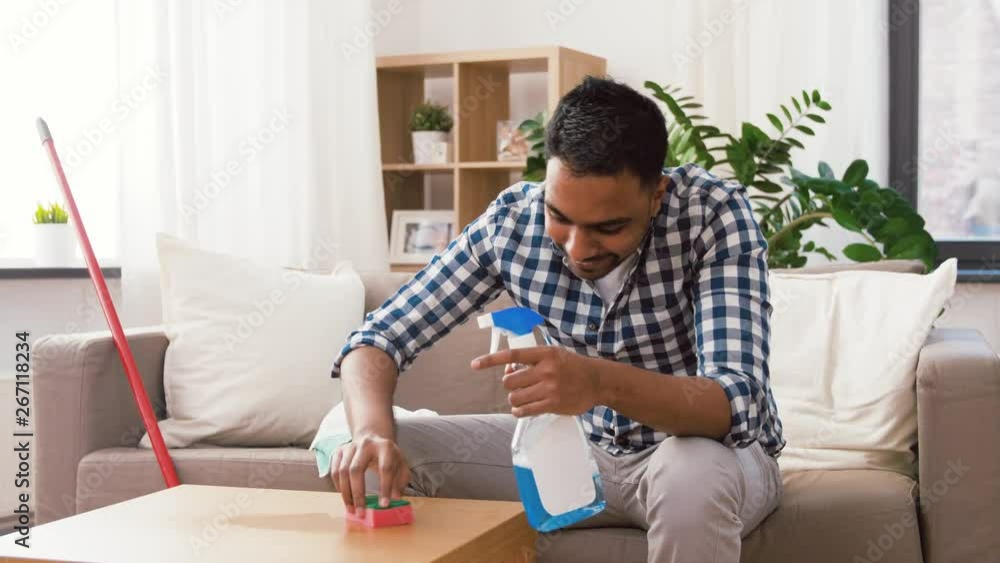 household and people concept - indian man cleaning table with detergent at home household and people concept - indian man cleaning table with detergent at home