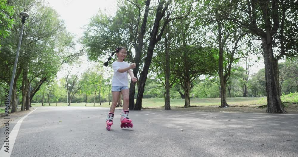 Asian little girl playing roller blade on the road at park. concept of activity holiday, learning development and life experience. 4K resolution and slow motion. Asian little girl playing roller blade on the road at park. concept of activity holiday, learning development and life experience. 4K resolution and slow motion.