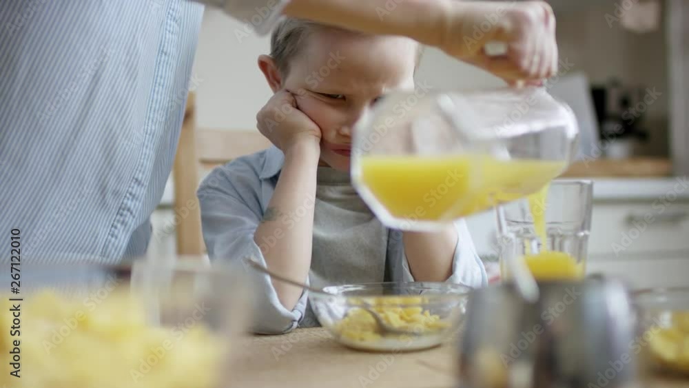 boy disspaointed with food and dotn want to eat while his mother add juice to his sister boy disspaointed with food and dotn want to eat while his mother add juice to his sister