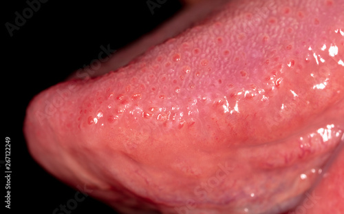 Tongue in the mouth of a man on a black background.
