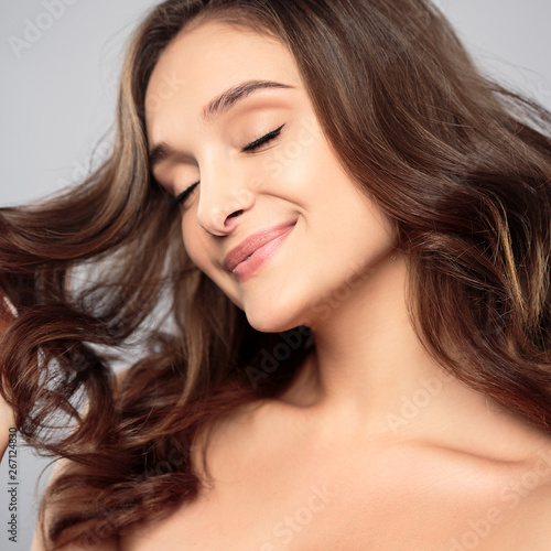 Brunette girl with healthy curly hair and natural make up . Beautiful model woman with wavy hairstyle .Care and beauty