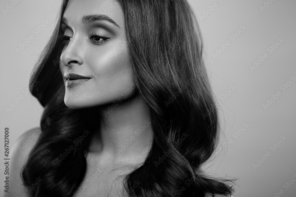 Brunette girl with healthy curly hair and natural make up . Beautiful model woman with wavy hairstyle .Care and beauty Brunette girl with healthy curly hair and natural make up . Beautiful model woman with wavy hairstyle .Care and beauty