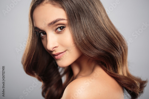 Brunette girl with healthy curly hair and natural make up . Beautiful model woman with wavy hairstyle .Care and beauty