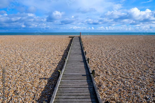 long straight wooden pathway on pebble beach photo
