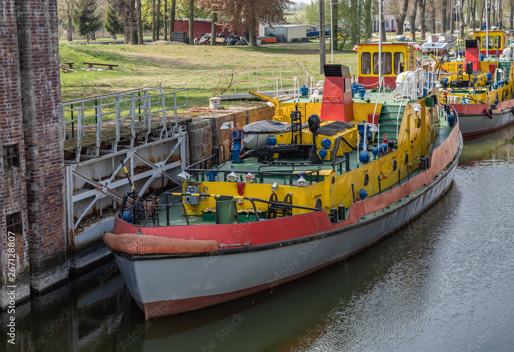 Sluice, water gate with colorful tugboats parked along the berth in Sobieszewo in Poland.