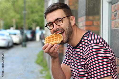 Cute guy eating a waffle in Brussels  Belgium