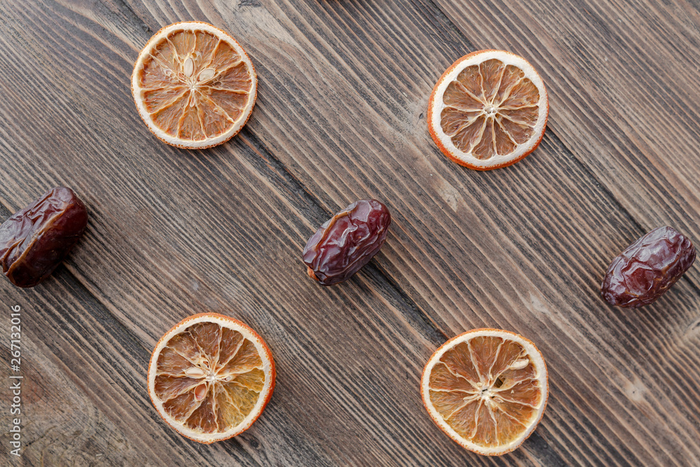 Orange chips, dried orange slices, and date fruits on wooden backgrond. Horizontal image. Top view, flat lay. Copy space