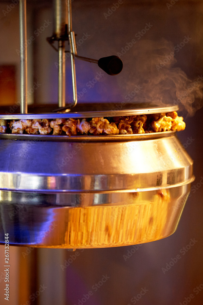 Cooking steaming popcorn in the cinema machine. Metal bowl and steam.