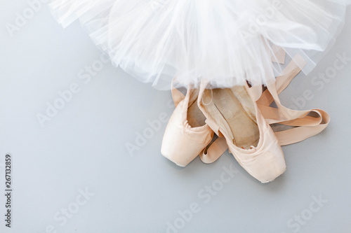 Ballet pointe shoes and white tutu skirt on gray background. Concept of dance, spring, ballet school, ballerinas clothes, stuff and things. Top view, flat lay. Copy space.