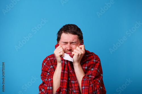 A sick man, wrapped in a blanket, is holding a white handkerchief.