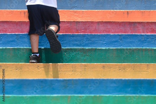 Lower part of a boy in casual shoe walking up outdoor colorful stair,children lifestyle successful concept