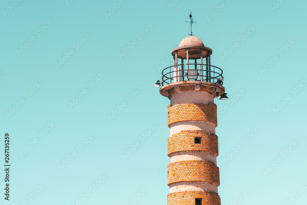 Old Brick Stone Lighthouse At Sea On Blue Sky