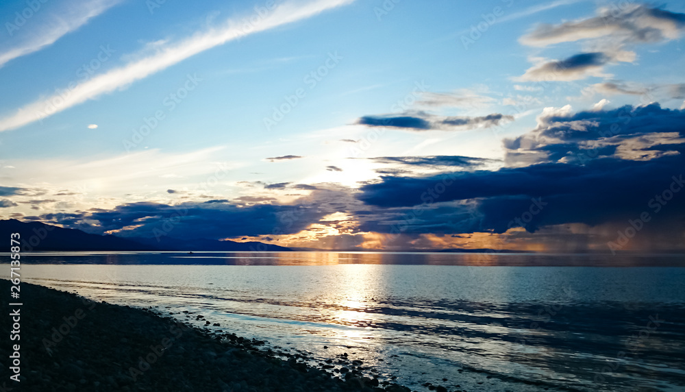 Obraz premium Sunset on Lake Baikal. Evening, rain, clouds, sun. Dramatic sky. Atmospheric landscape. The shore of Lake Baikal. Russia.