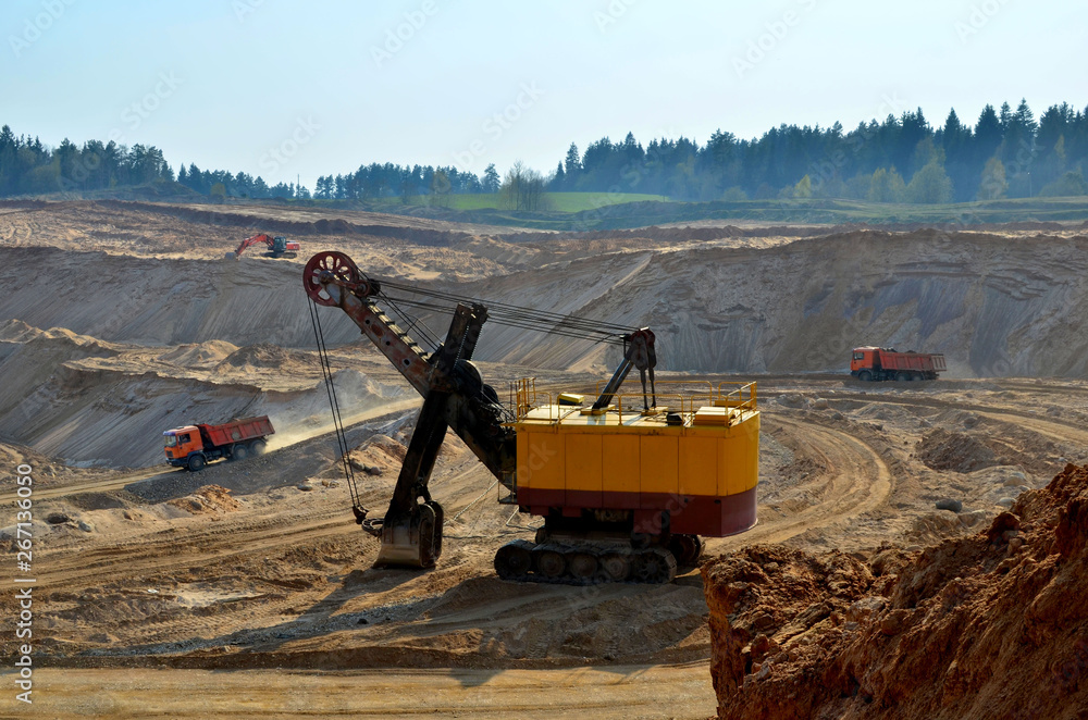 View of the open pit mining. A large number of excavators and mining trucks work in a quarry for transporting sand to a crushing plant - Image