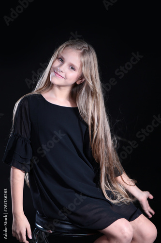 Portrait of a blonde girl with long hair on a black background. Emotional portrait.The girl shows different emotions on the face. Plays with long hair.