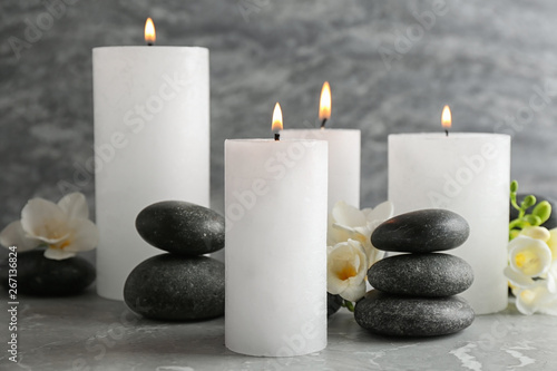 Burning candles, spa stones and flowers on table