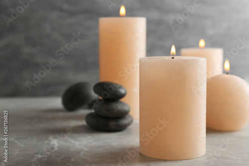 Burning candles and spa stones on table. Space for text