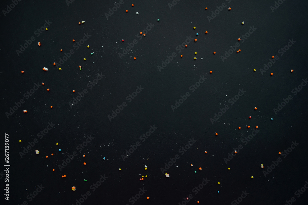 Colorful cake sprinkles scattered over black background with copyspace Colorful cake sprinkles scattered over black background with copyspace