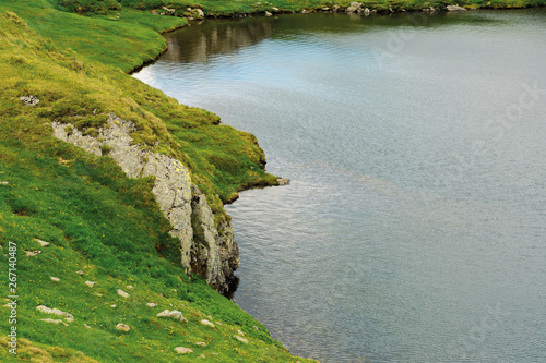 glacier mountain lake in summer. beautiful nature scenery. wonderful background with water, grass, and rocks