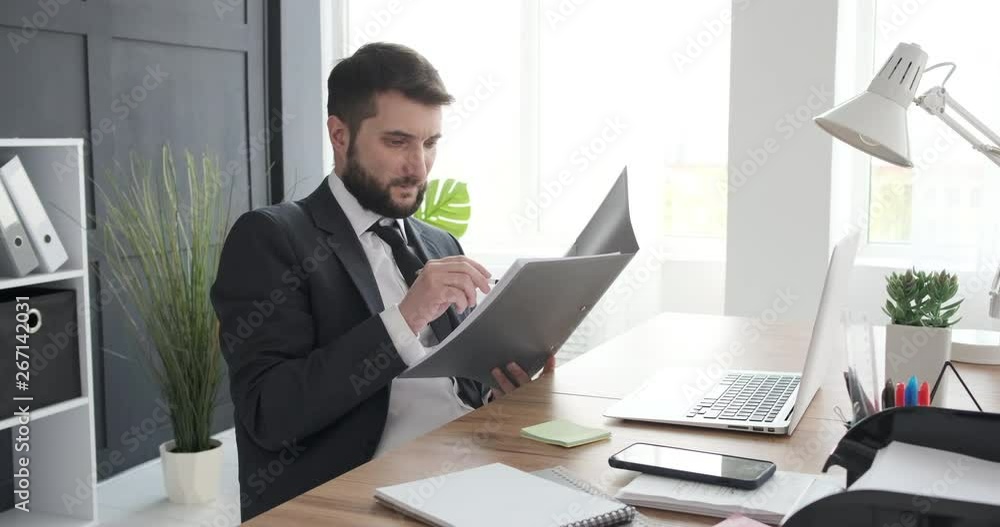 Businessman reading documents and working on laptop Businessman reading documents and working on laptop