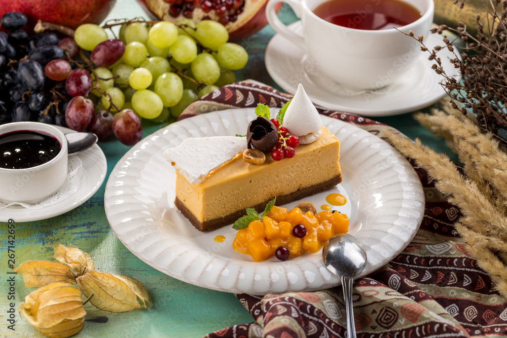 Square Earl Gray Rare Cheesecake With red berries and Cup of tea on blue wooden table Square Earl Gray Rare Cheesecake With red berries and Cup of tea on blue wooden table