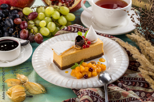 Square Earl Gray Rare Cheesecake With red berries and Cup of tea on blue wooden table