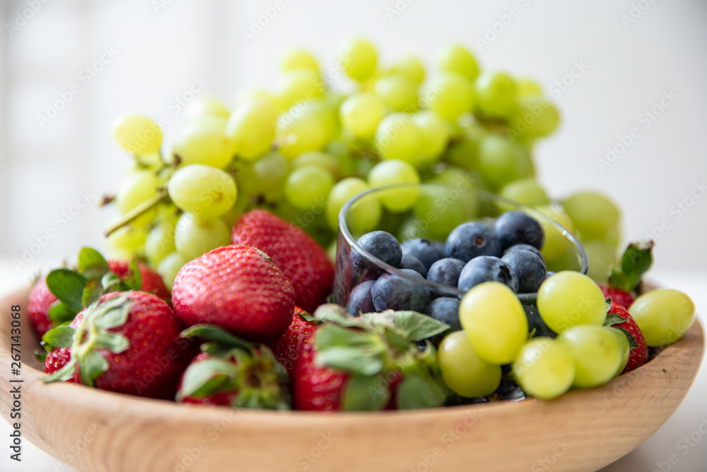 Wooden bowl with fruits: strawberries, blueberries and green grapes. Wooden bowl with fruits: strawberries, blueberries and green grapes.