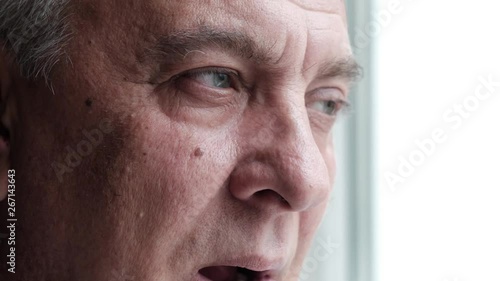 Sad tired elderly man yawning and looking out the window