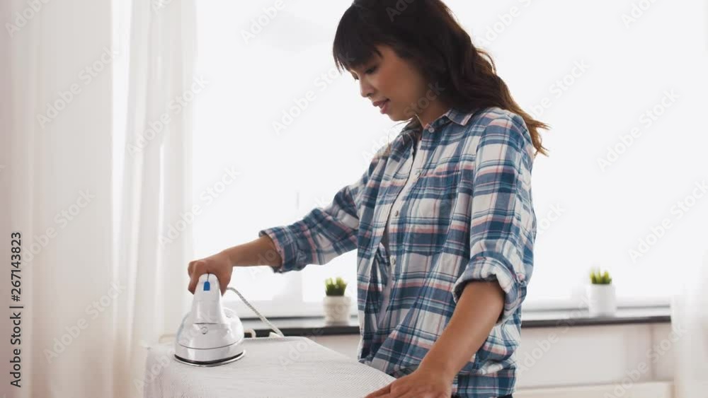 housework, laundry and housekeeping concept - asian woman ironing bed linen on board at home housework, laundry and housekeeping concept - asian woman ironing bed linen on board at home