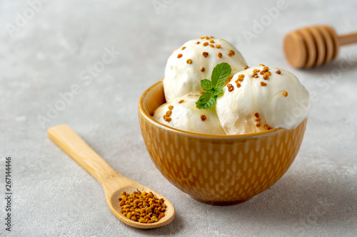 Tasty ice cream with bee pollen and honey in bowl on table	