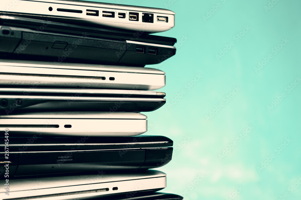 Stack of laptops / notebooks on turquoise background with copy space