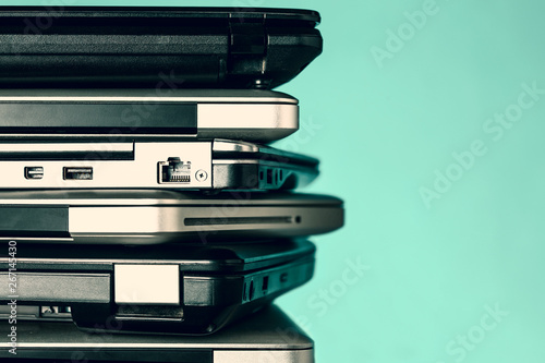 Stack of laptops / notebooks on turquoise background with copy space
