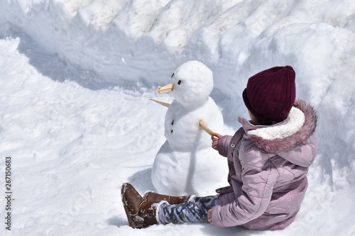 A child playing with a snowman