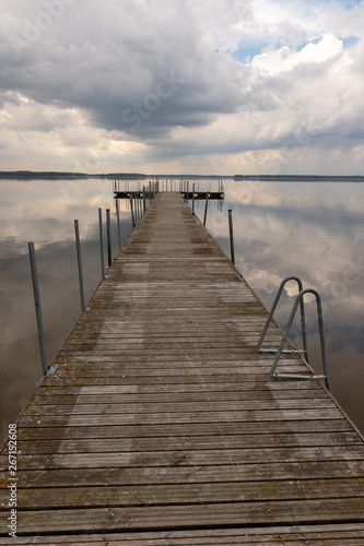 A small bridge over the lake. Reflection of clouds on the lake's surface.
