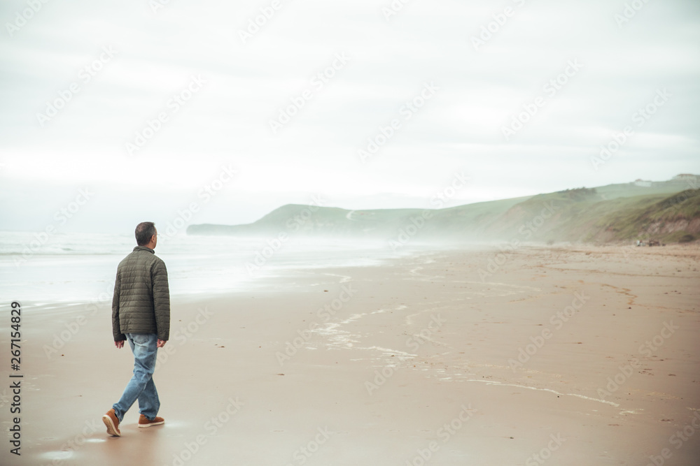 Man walking at beach in Cantabria, north of Spain Man walking at beach in Cantabria, north of Spain