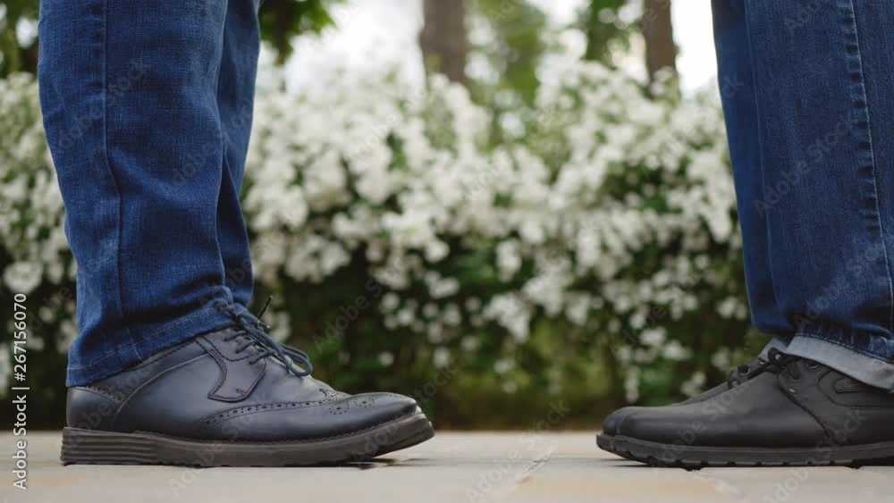 Close-up of two guys legs meet and gently kiss on a romantic date. Close-up of two guys legs meet and gently kiss on a romantic date.