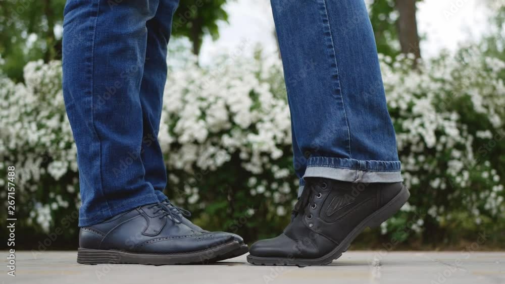 Close-up of two guys legs meet and gently kiss on a romantic date. Close-up of two guys legs meet and gently kiss on a romantic date.