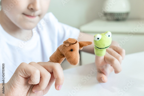 A caucasian boy playing finger puppets, toys, dolls - figures of animals, heroes of the puppet theatre put on fingers of human hand