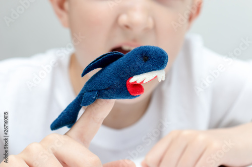 A caucasian boy playing different roles by using finger puppets, toys for expressing his emotions, agression, fear and freandship as a part of psychotherapy photo