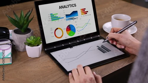 Young business woman drawing growing graphic lines and diagrams animated on tochpad of laptop computer. Screen shows colorful analytic with diagrams. photo