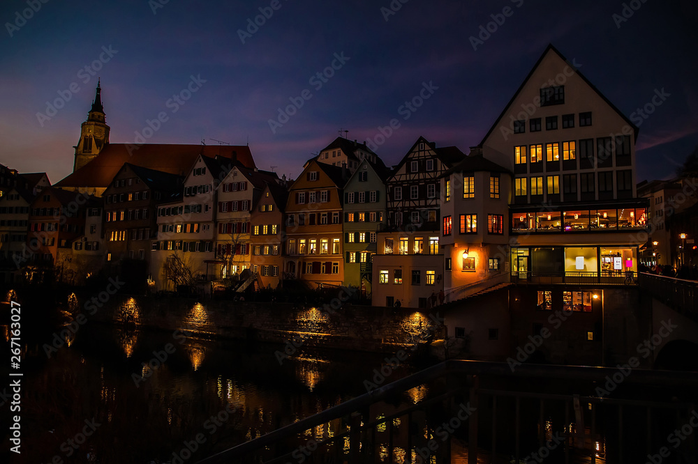Fototapeta premium Old houses with luminous windows in the evening