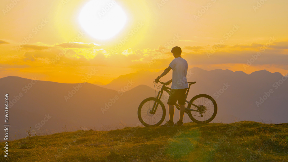LENS FLARE: Flying towards a fit male tourist watching the sunset after cycling. LENS FLARE: Flying towards a fit male tourist watching the sunset after cycling.