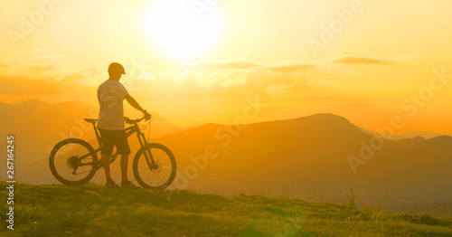 LENS FLARE: Man rests after a bike trip and observes the evening landscape.