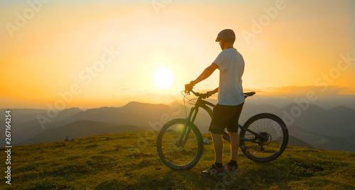 LENS FLARE: Young male tourist observes the landscape before mountain biking