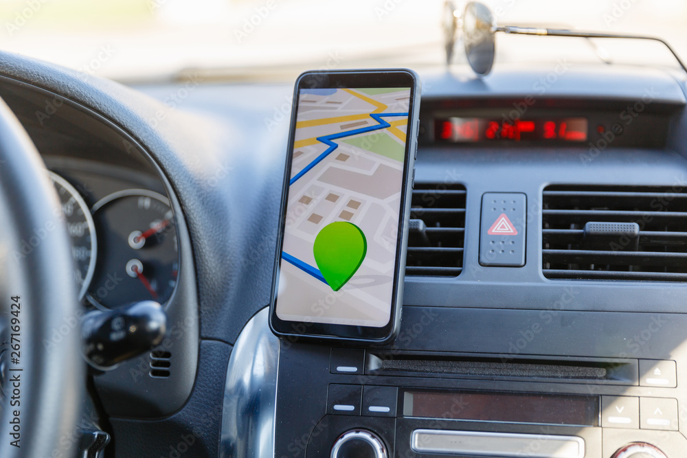 Arrival or destination point on the map in the phone on the dashboard background. Black mobile phone with GPS map navigation is fixed in the installation. App map for traveling with route
